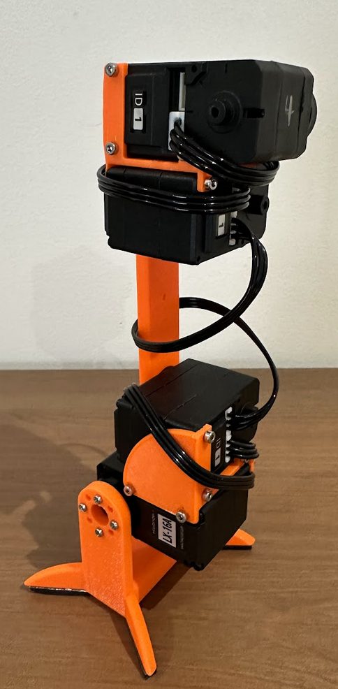 A single assembled robot leg standing upright, two black motors stacked with an orange bar and a clawed orange foot.
